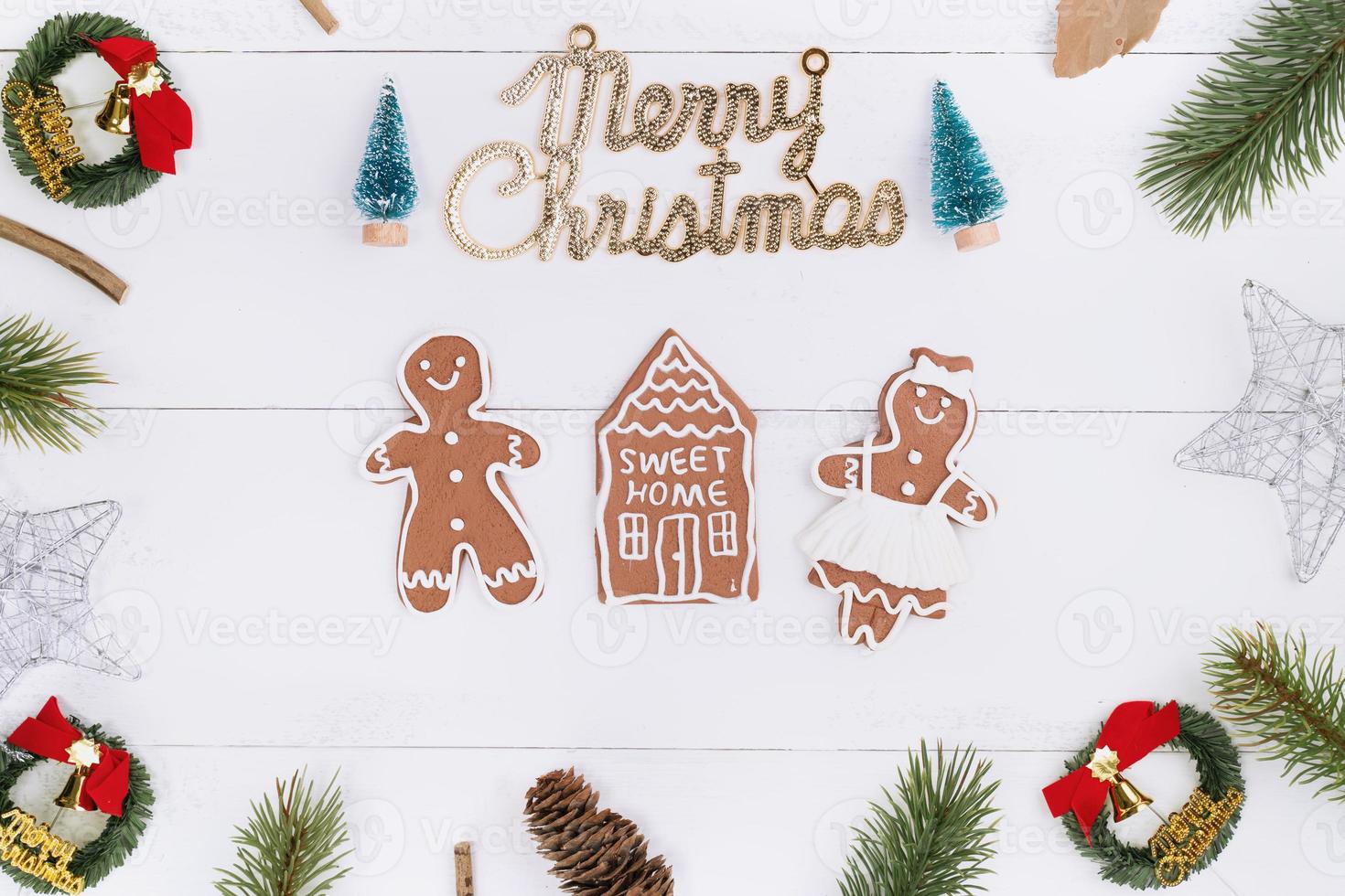 objetos de decoración de composición de concepto de navidad, corona de rama de abeto, galleta de hombre de pan de jengibre aislada en una mesa de madera blanca, vista superior, capa plana foto