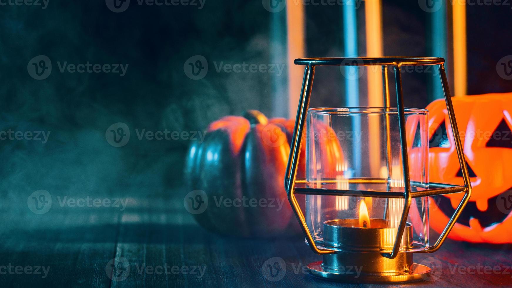 Halloween holiday concept design of pumpkin, candle, spooky decorations with green tone smoke around on a dark wooden table, close up shot. photo