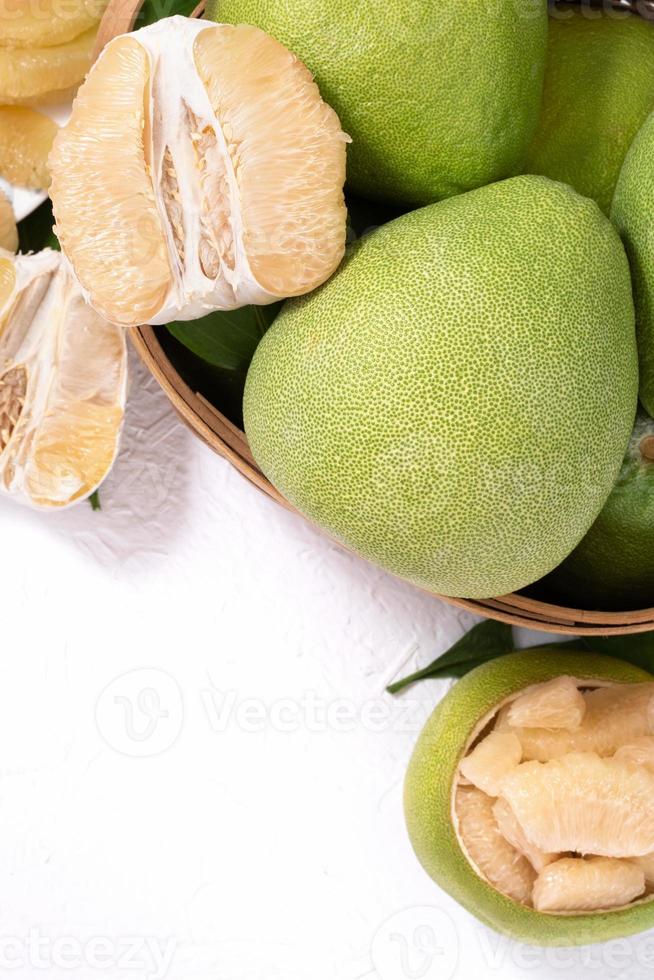 Fresh pomelo, pummelo, grapefruit, shaddock on white cement background in bamboo basket. Autumn seasonal fruit, top view, flat lay, tabletop shot. photo