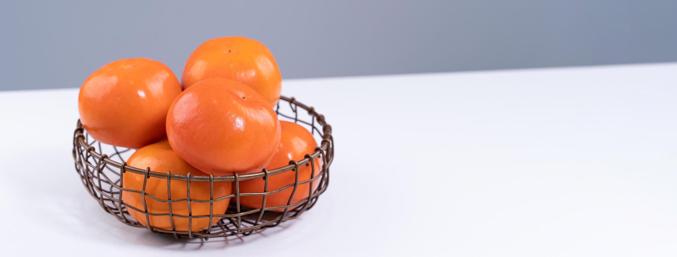 Fresh beautiful sliced sweet persimmon kaki isolated on white kitchen table with gray blue background, Chinese lunar new year design concept, close up. photo