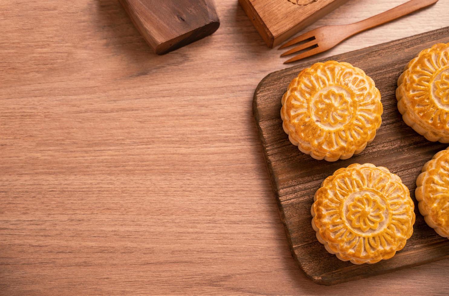 Round shaped fresh baked moon cake pastry - Chinese moonckae for Mid-Autumn Moon Festival on wooden background and serving tray, top view, flat lay. photo