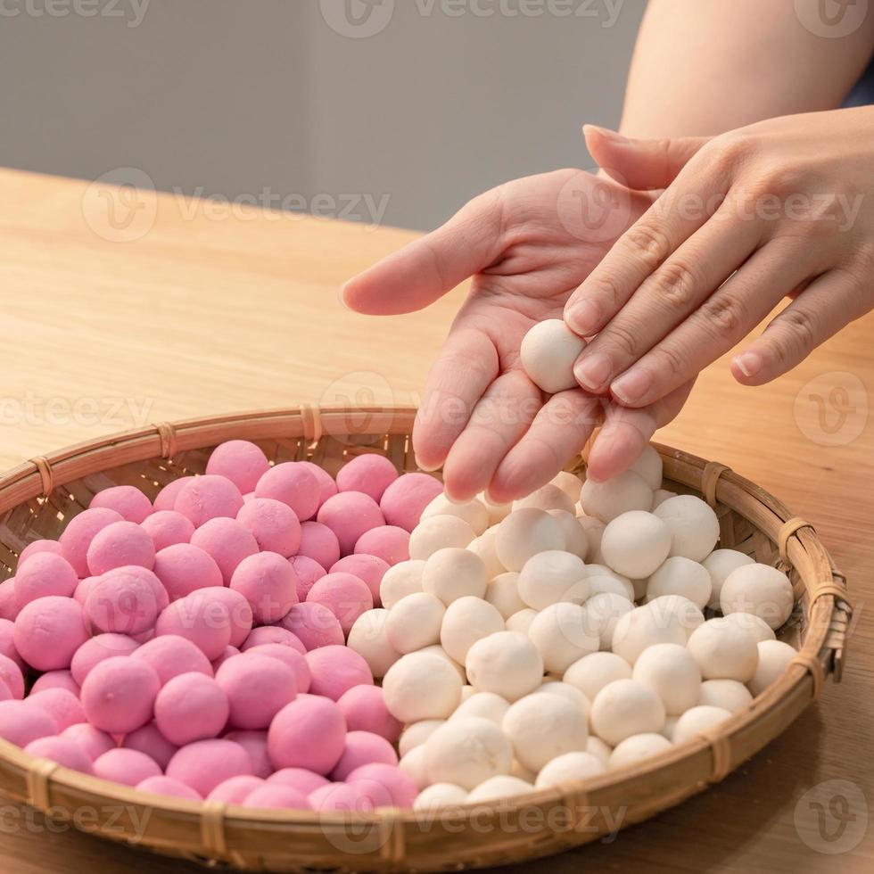 una mujer de asia está haciendo tang yuan, yuan xiao, albóndigas de arroz de comida tradicional china en rojo y blanco para el año nuevo lunar, festival de invierno, de cerca. foto