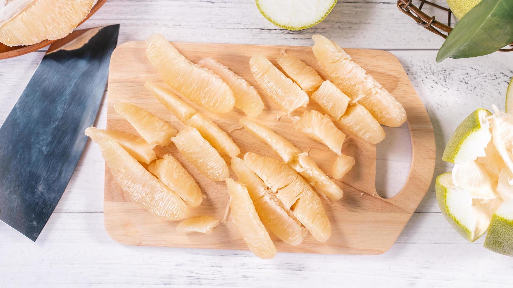 Fresh peeled pomelo, pummelo, grapefruit, shaddock on bright wooden background. Autumn seasonal fruit, top view, flat lay, tabletop shot. photo