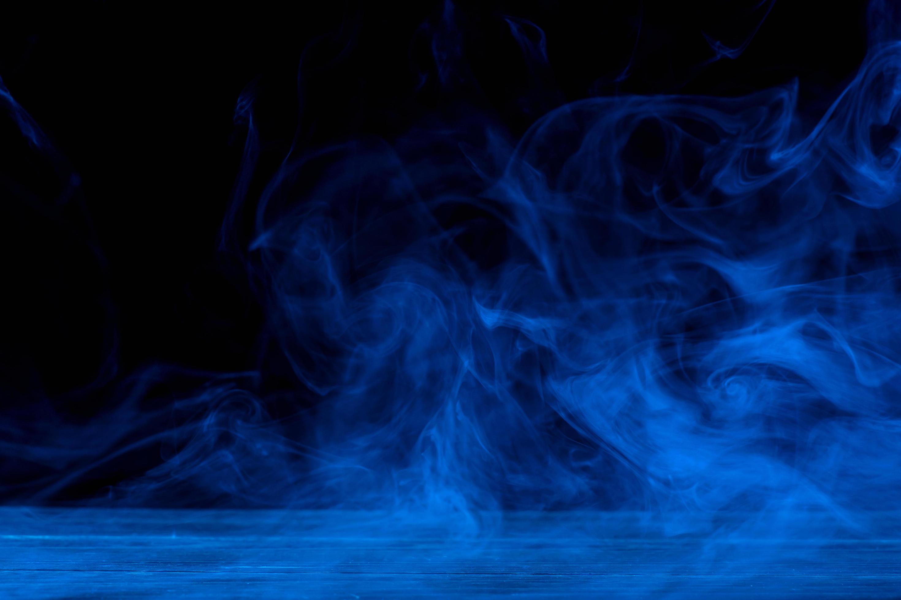Conceptual image of blue smoke isolated on dark black background and