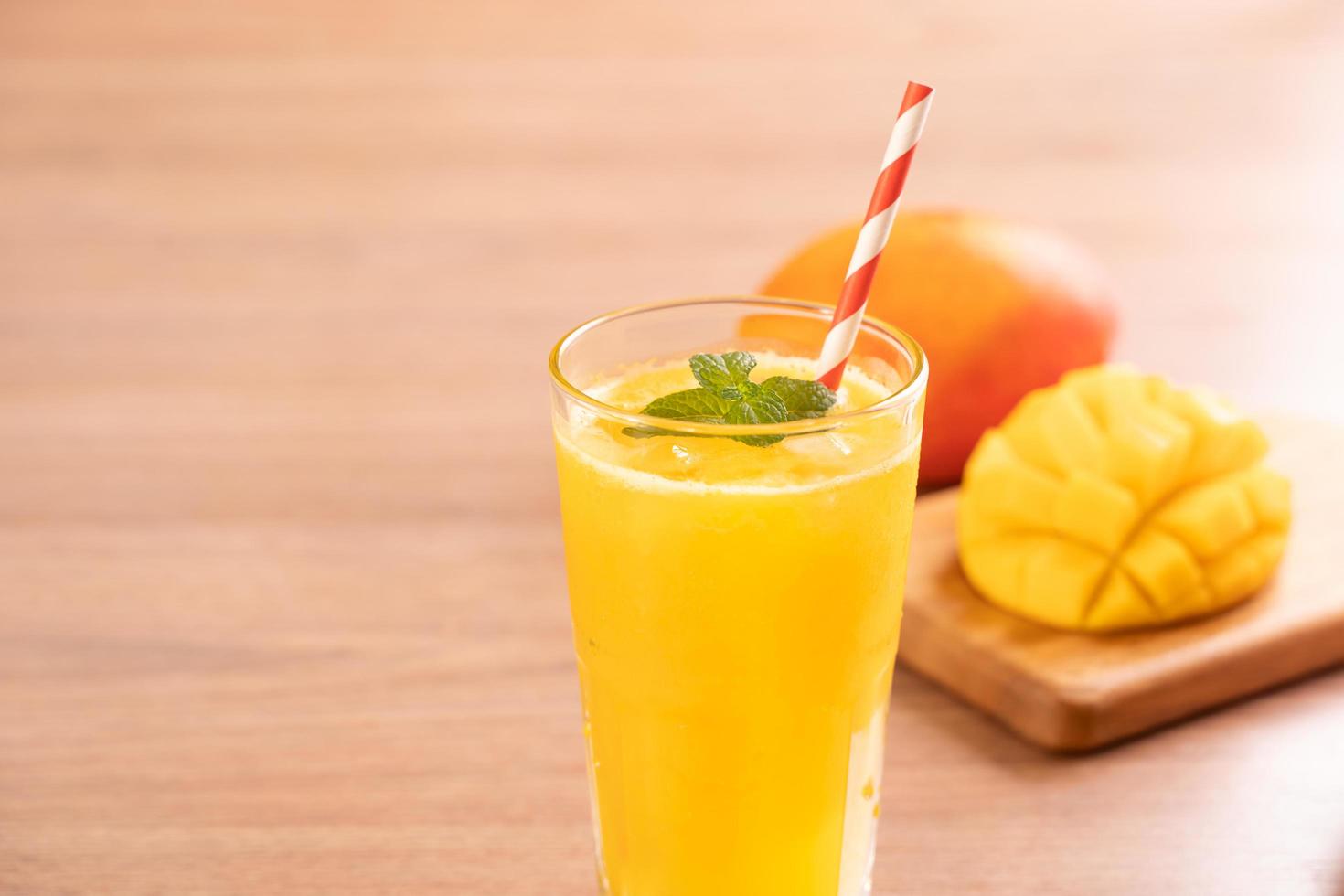 Fresh mango juice with beautiful chopped pulp flesh on bright wooden table background. Tropical fruit drink design concept. Close up, copy space. photo