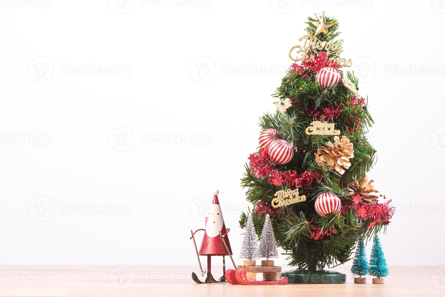 Decorated cute Christmas tree on a wooden floor with white background and toys, blank for festive design concept, close up. photo