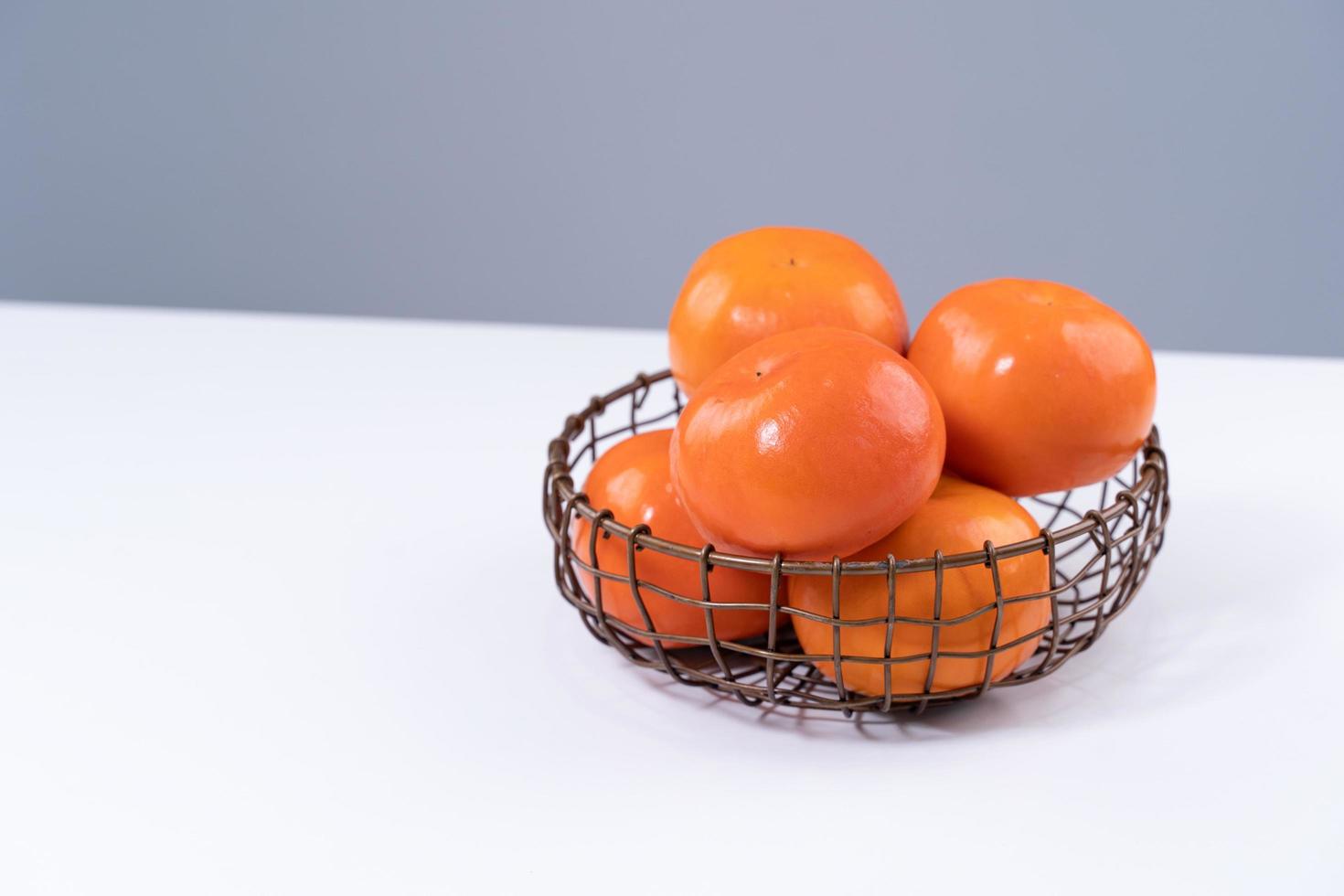 Fresh beautiful sliced sweet persimmon kaki isolated on white kitchen table with gray blue background, Chinese lunar new year design concept, close up. photo