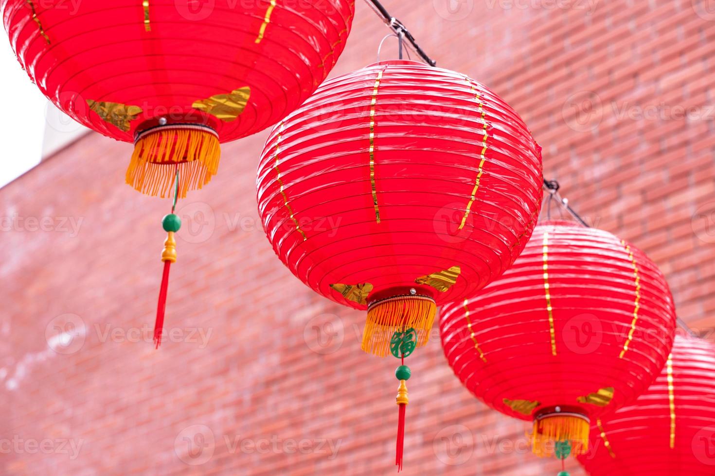 Beautiful round red lantern hanging on old traditional street, concept of Chinese lunar new year festival, close up. The undering word means blessing. photo