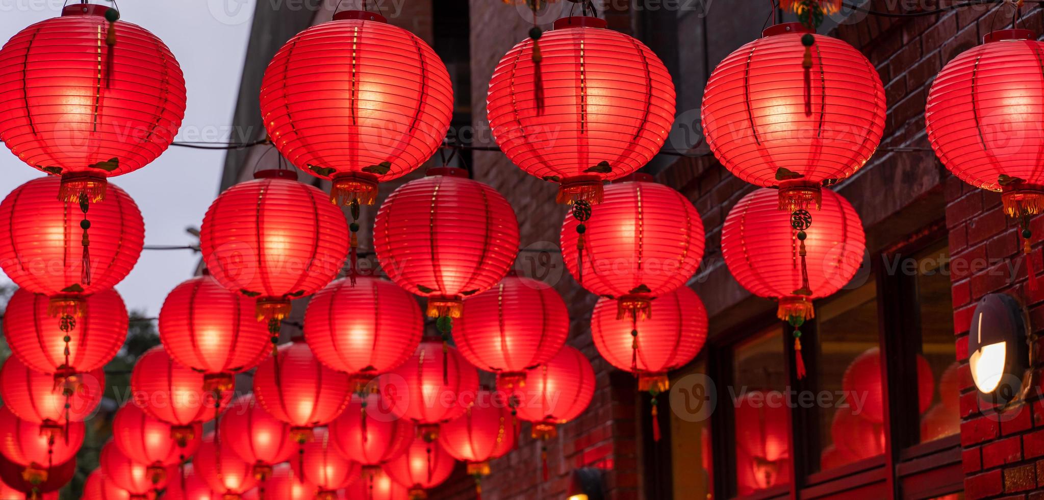 Beautiful round red lantern hanging on old traditional street, concept of Chinese lunar new year festival, close up. The undering word means blessing. photo