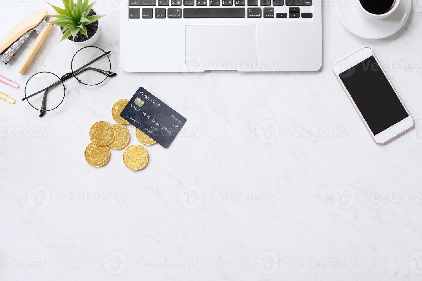 Concept of online payment with credit card with smart phone, laptop computer on office desk on clean bright marble table background, top view, flat lay photo