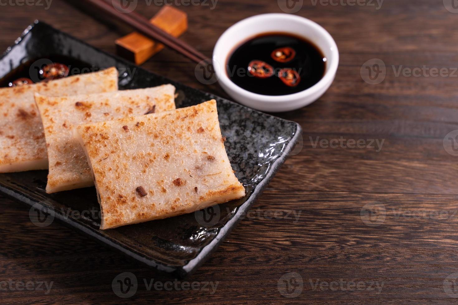 Delicious turnip cake, Chinese traditional local dish radish cake in restaurant with soy sauce and chopsticks, close up, copy space. photo