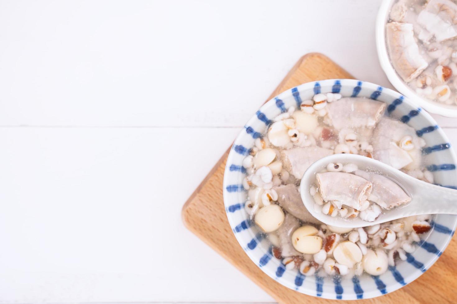 Tasty Four Tonics Herb Flavor Soup, Taiwanese traditional food with herbs, pork intestines on white wooden table, close up, flat lay, top view. photo