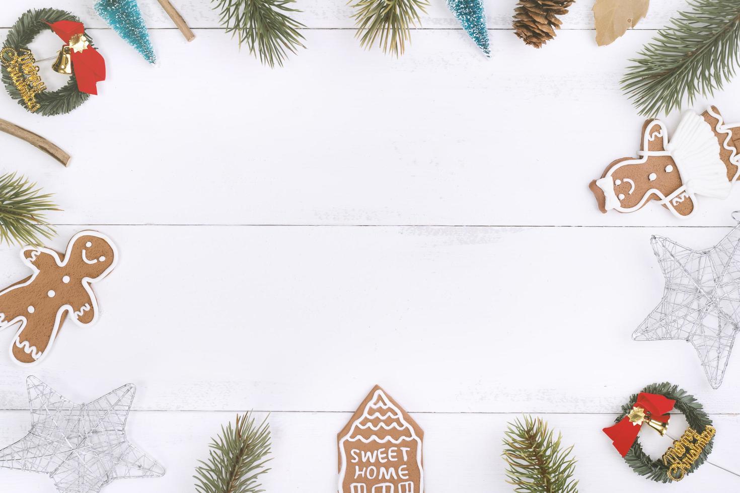 objetos de decoración de composición de concepto de navidad, corona de rama de abeto, galleta de hombre de pan de jengibre aislada en una mesa de madera blanca, vista superior, capa plana foto