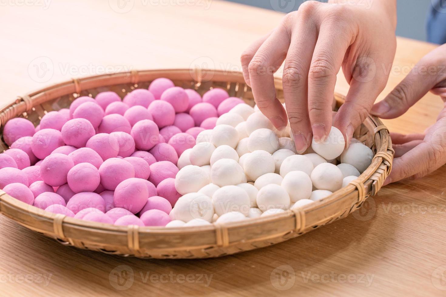 una mujer de asia está haciendo tang yuan, yuan xiao, albóndigas de arroz de comida tradicional china en rojo y blanco para el año nuevo lunar, festival de invierno, de cerca. foto