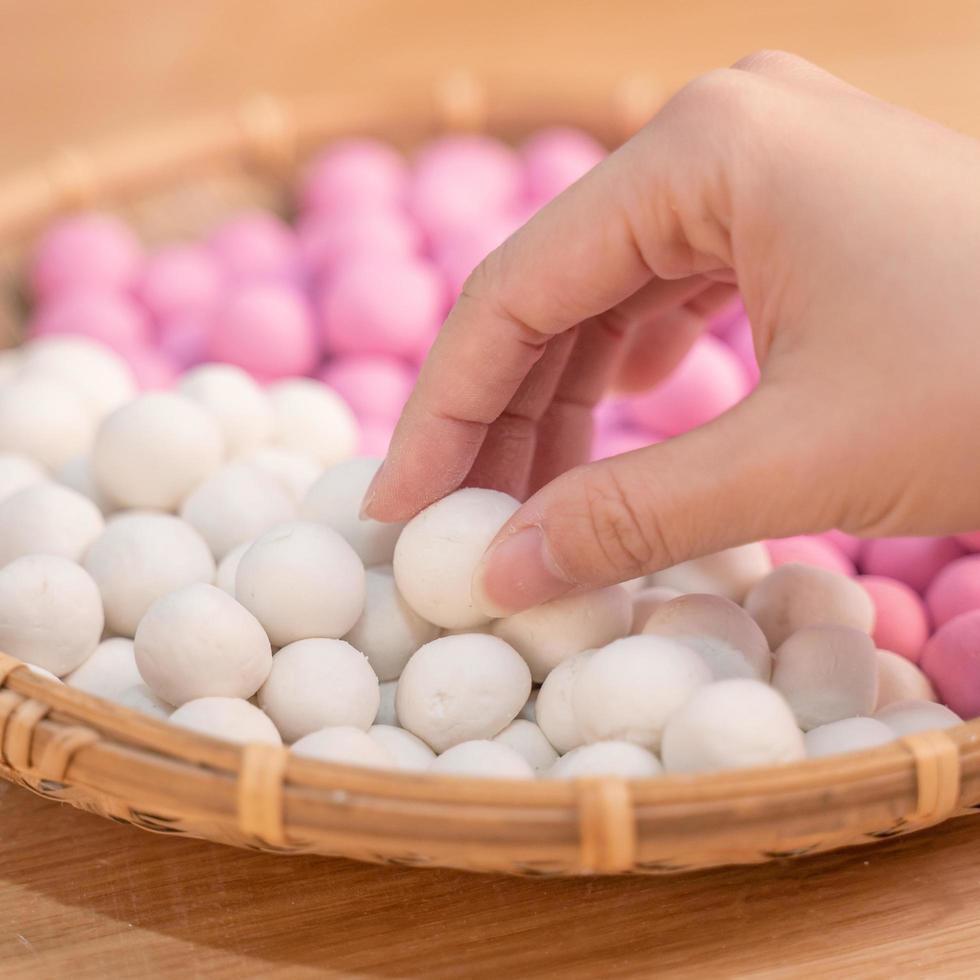 una mujer de asia está haciendo tang yuan, yuan xiao, albóndigas de arroz de comida tradicional china en rojo y blanco para el año nuevo lunar, festival de invierno, de cerca. foto