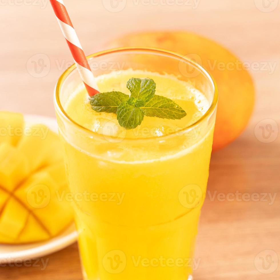 Fresh mango juice with beautiful chopped pulp flesh on bright wooden table background. Tropical fruit drink design concept. Close up, copy space. photo