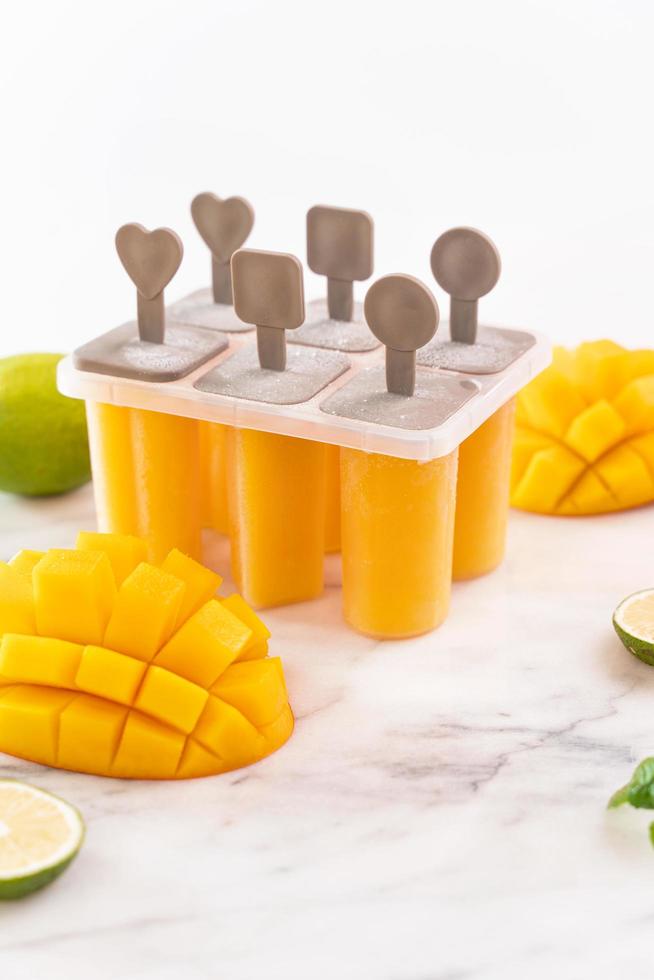 hielo de paleta de fruta de mango fresco en la caja de plástico sobre una mesa de mármol brillante. diseño de producto de concepto de estado de ánimo de verano, primer plano. foto