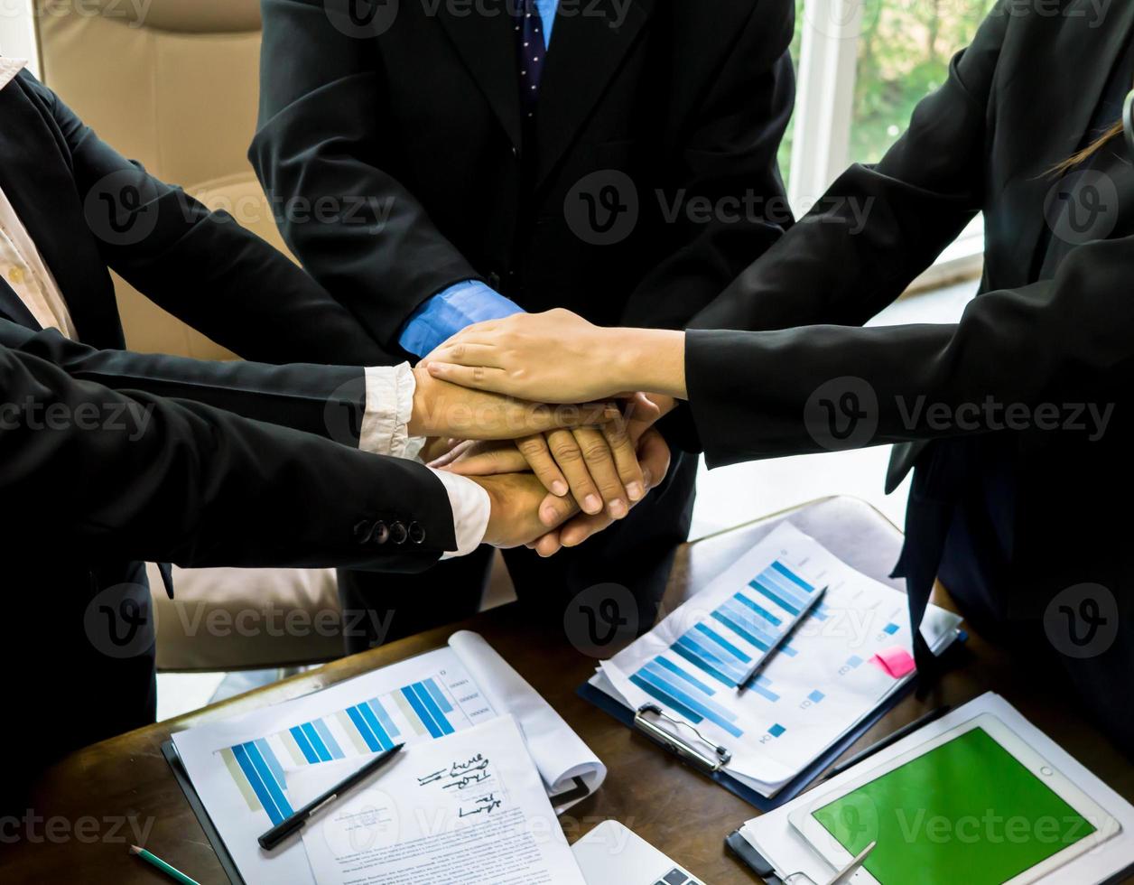 business team working at trendy loft office. Young mixed race group of people puts palm together on the centre. Teamwork of happy guys, colleagues. photo