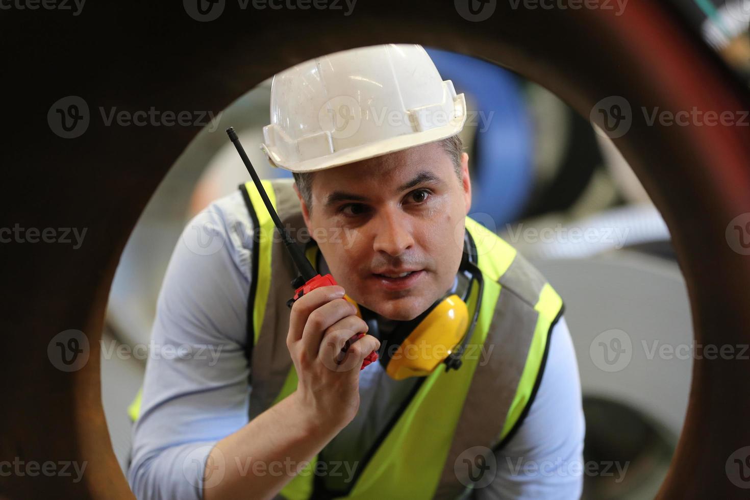 Men industrial engineer wearing a safety helmet while standing in a heavy industrial factory. The Maintenance looking of working at industrial machinery and check security system setup in factory. photo