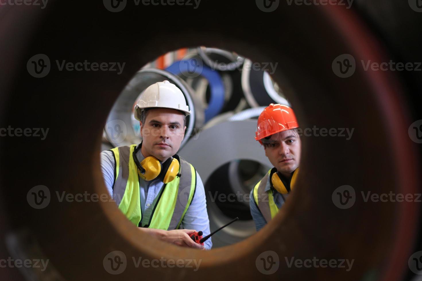 Men industrial engineer wearing a safety helmet while standing in a heavy industrial factory. The Maintenance looking of working at industrial machinery and check security system setup in factory. photo