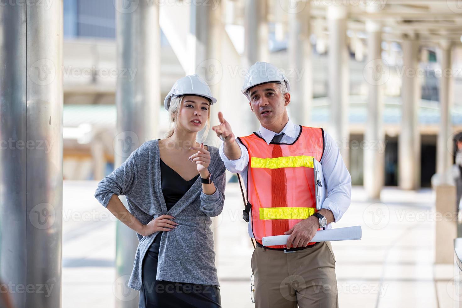 Contractor and architect looking at plan and talking about working on big project. Building in construction process interior. photo