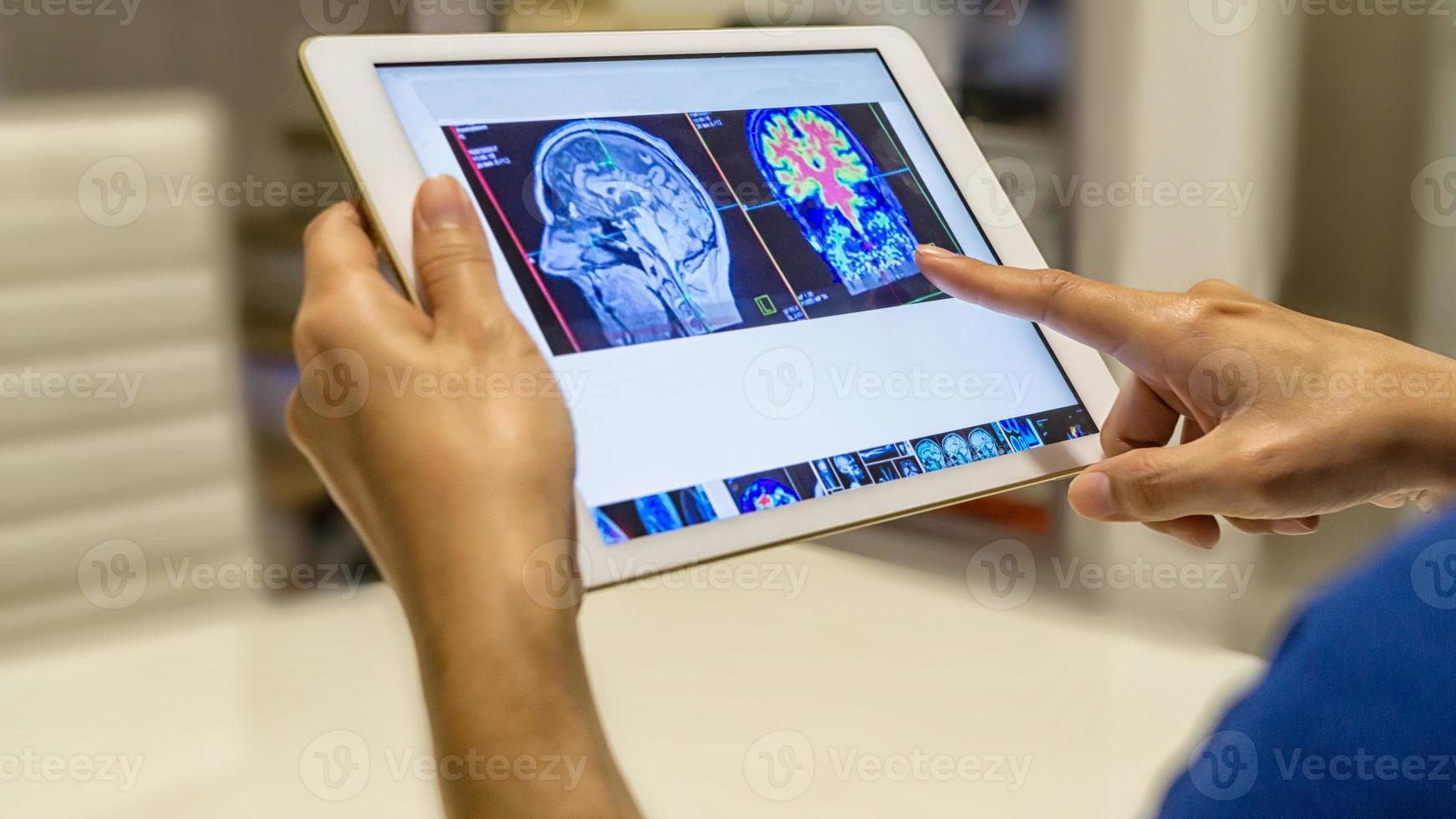 médico mirando la imagen radiológica del escaneo de rayos X del cerebro en la tableta para el diagnóstico médico foto