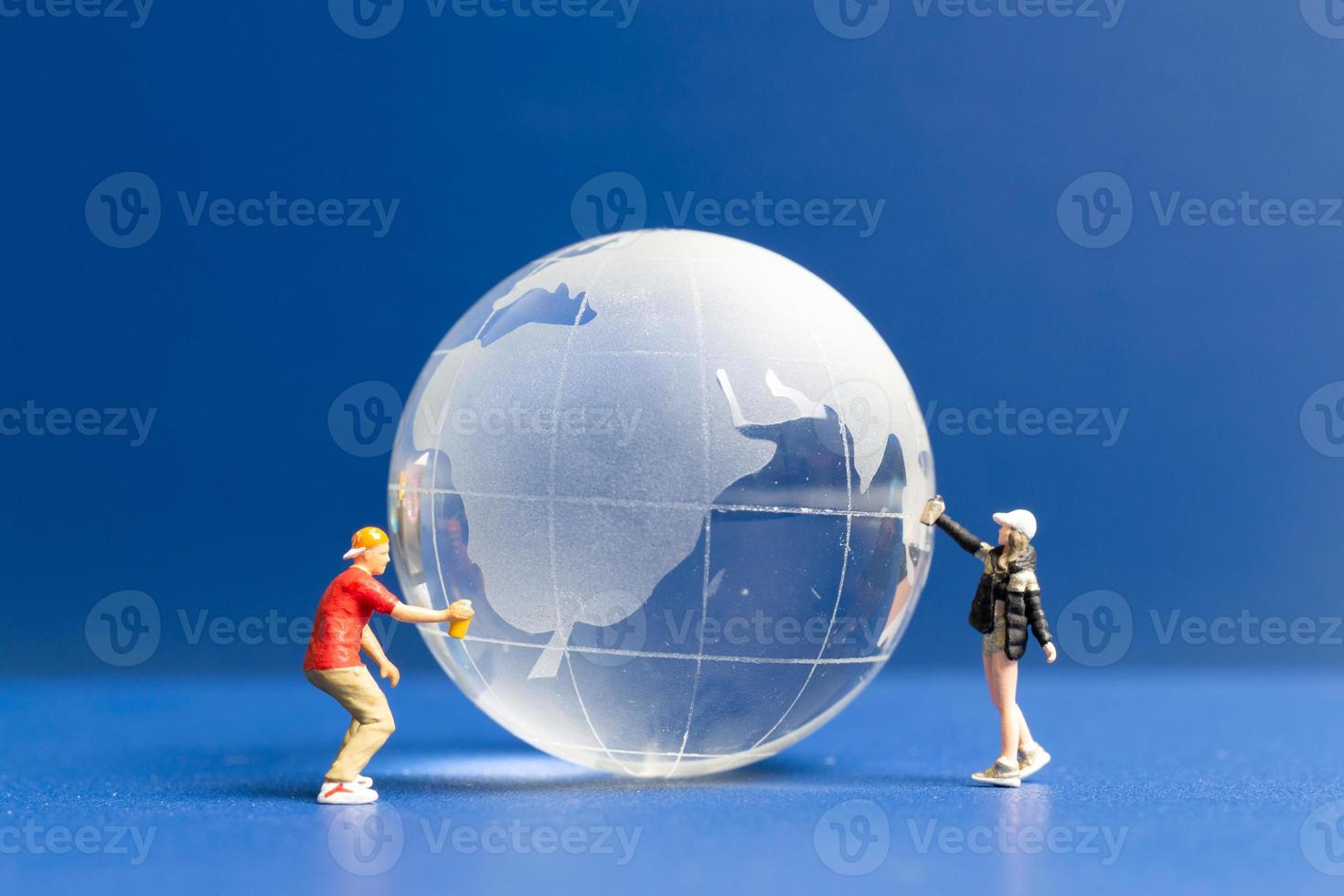 Miniature people Teenager spraying paint crytal globe on blue background photo