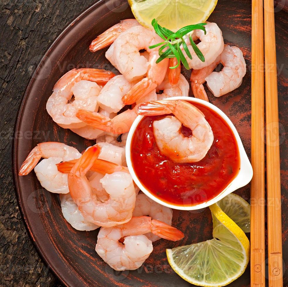 tails of shrimps with fresh lemon and rosemary in plate on wooden old background photo