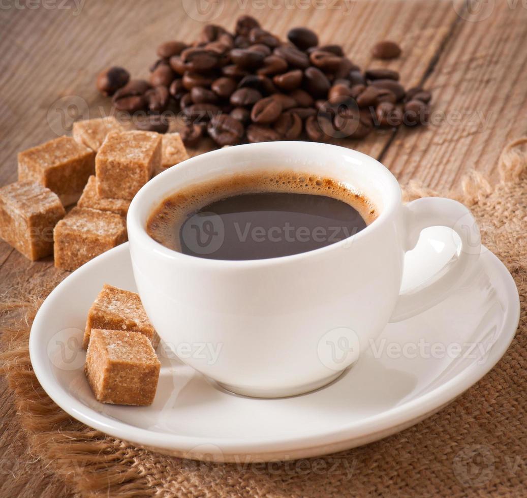 vista de cerca de una taza de café, azúcar moreno y granos de café foto