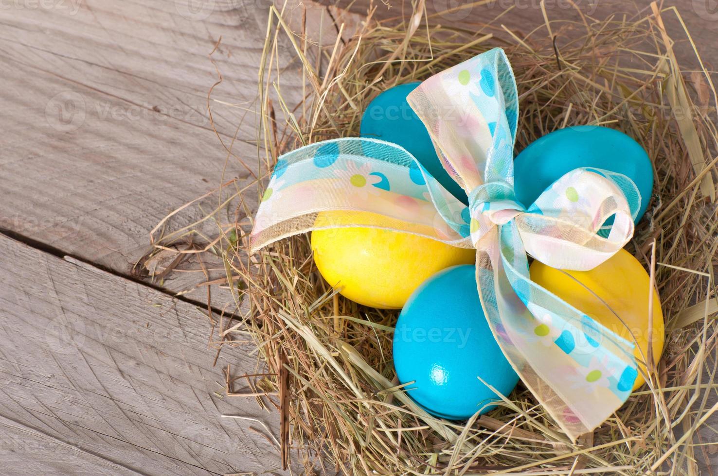 Huevos de Pascua en el nido sobre fondo de madera foto