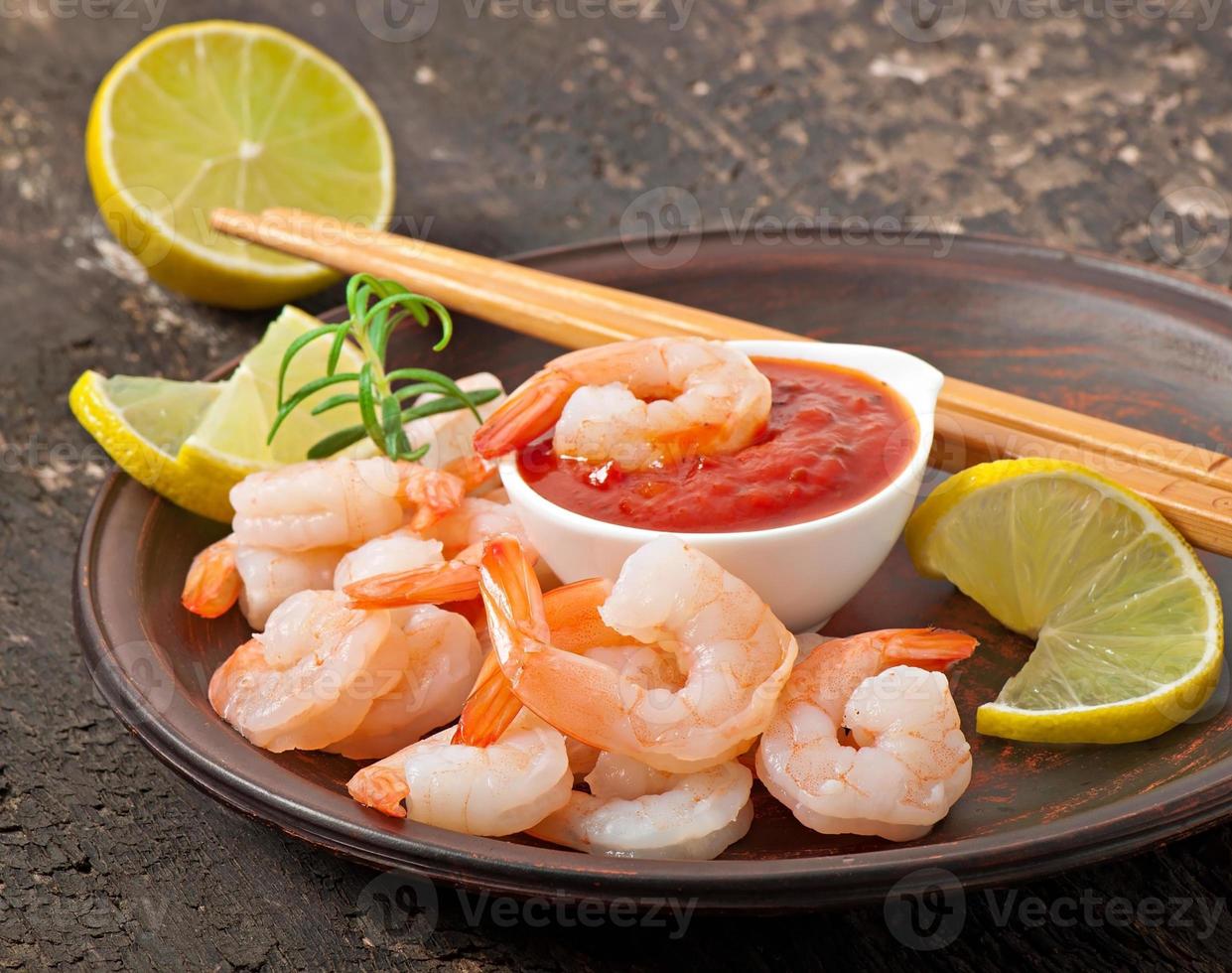 tails of shrimps with fresh lemon and rosemary in plate on wooden old background photo