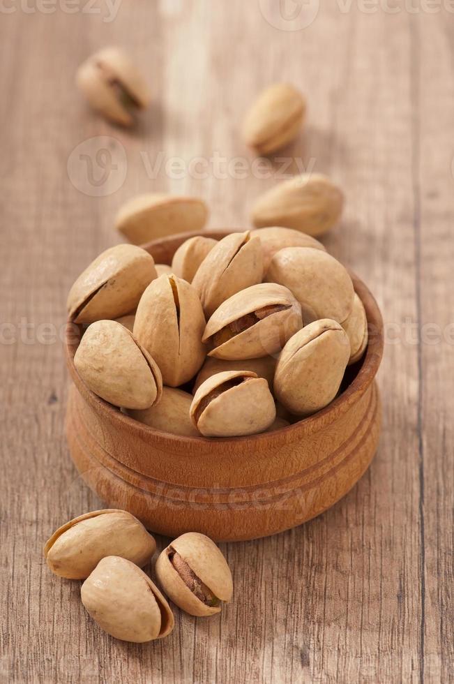 Cracked and Dried Pistachio Nuts In A Wooden Bowl photo