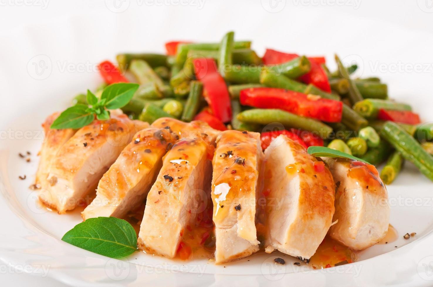 Chicken breast with vegetables and sauce decorated with basil leaves photo