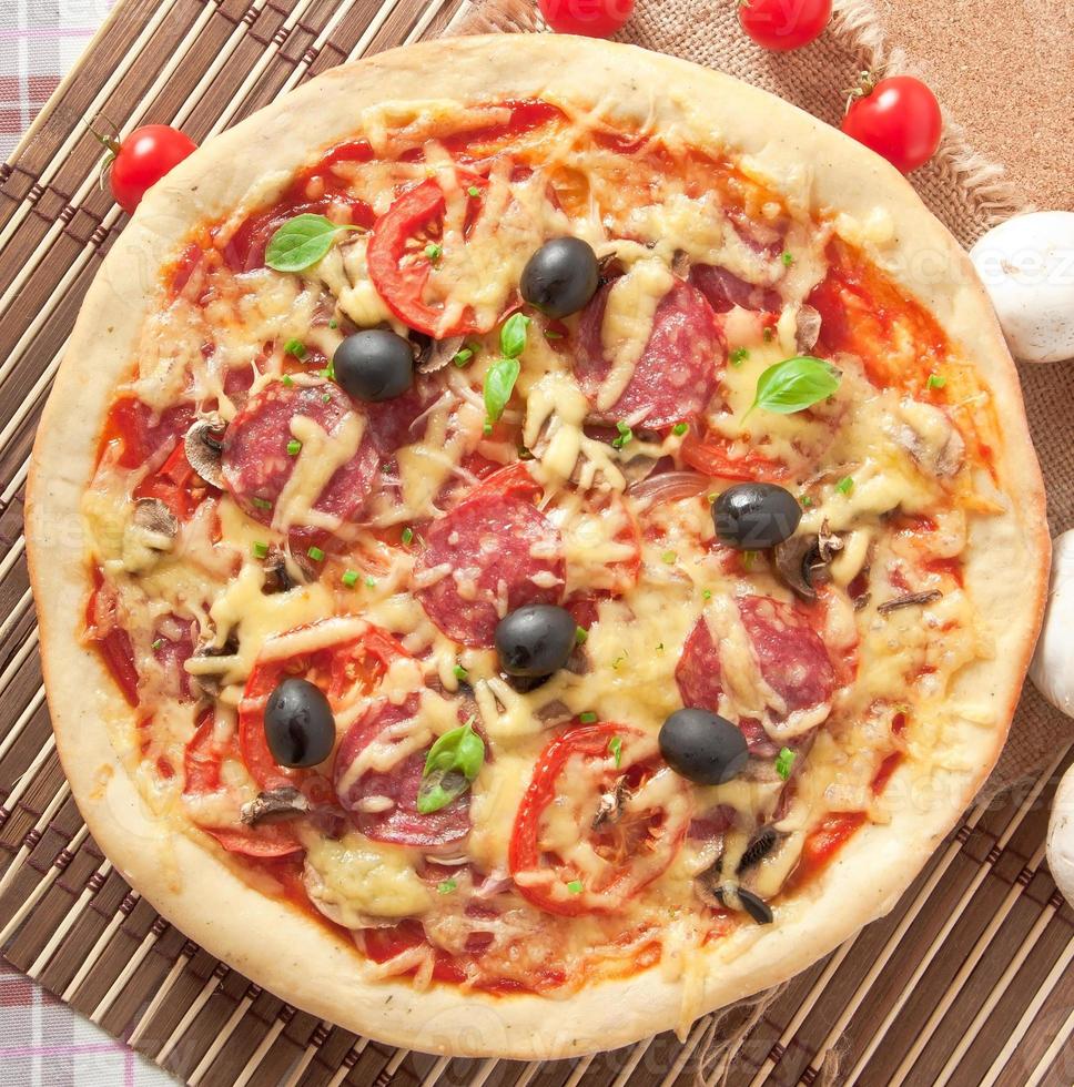 pizza con salami, tomates y champiñones foto