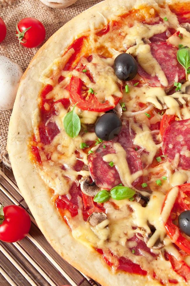 pizza with salami, tomatoes and mushrooms photo