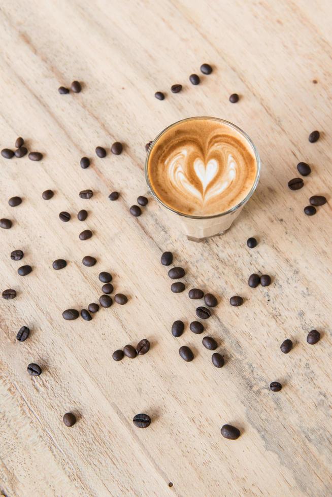 una taza de café con leche con granos de café en la mesa de madera. foto