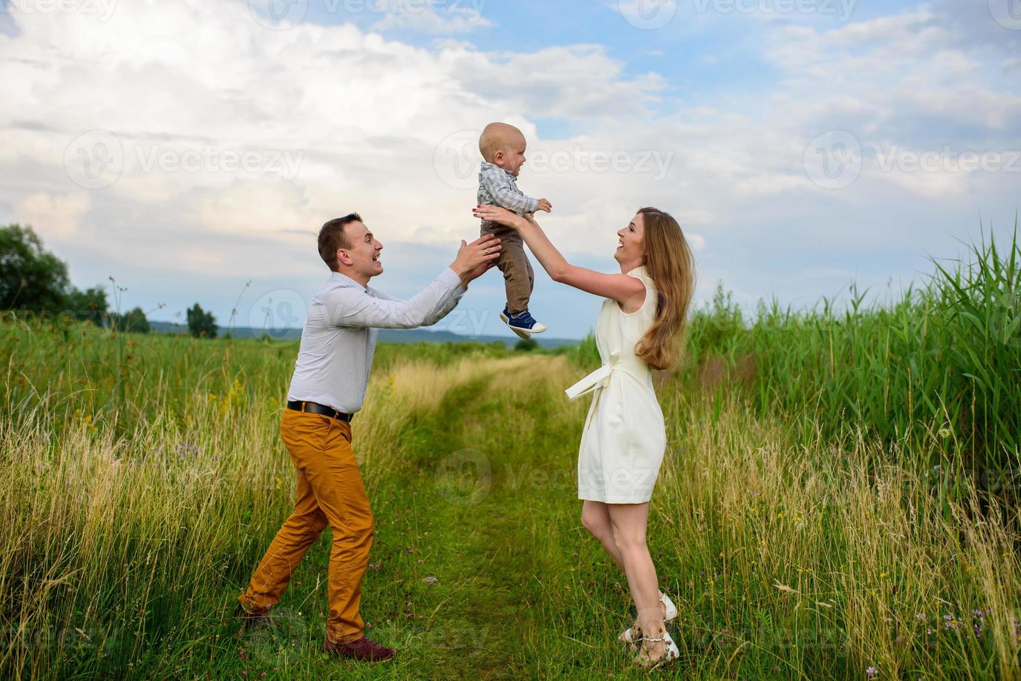 Father and mother lead their one-year-old son by the hand. photo