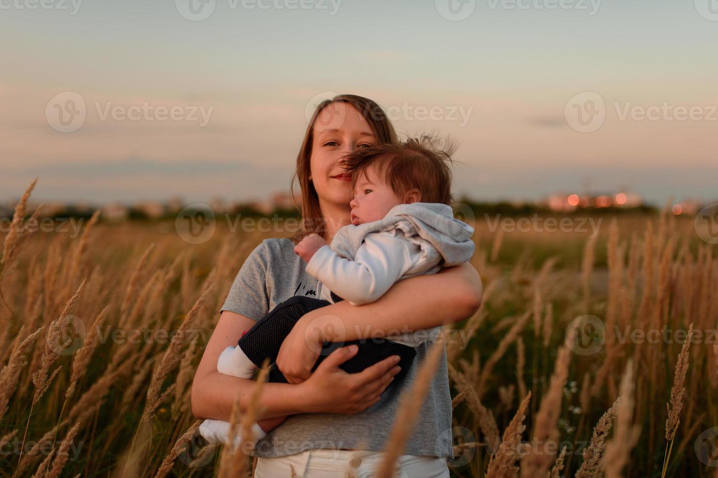 una madre camina por el campo con su hijita en brazos. foto