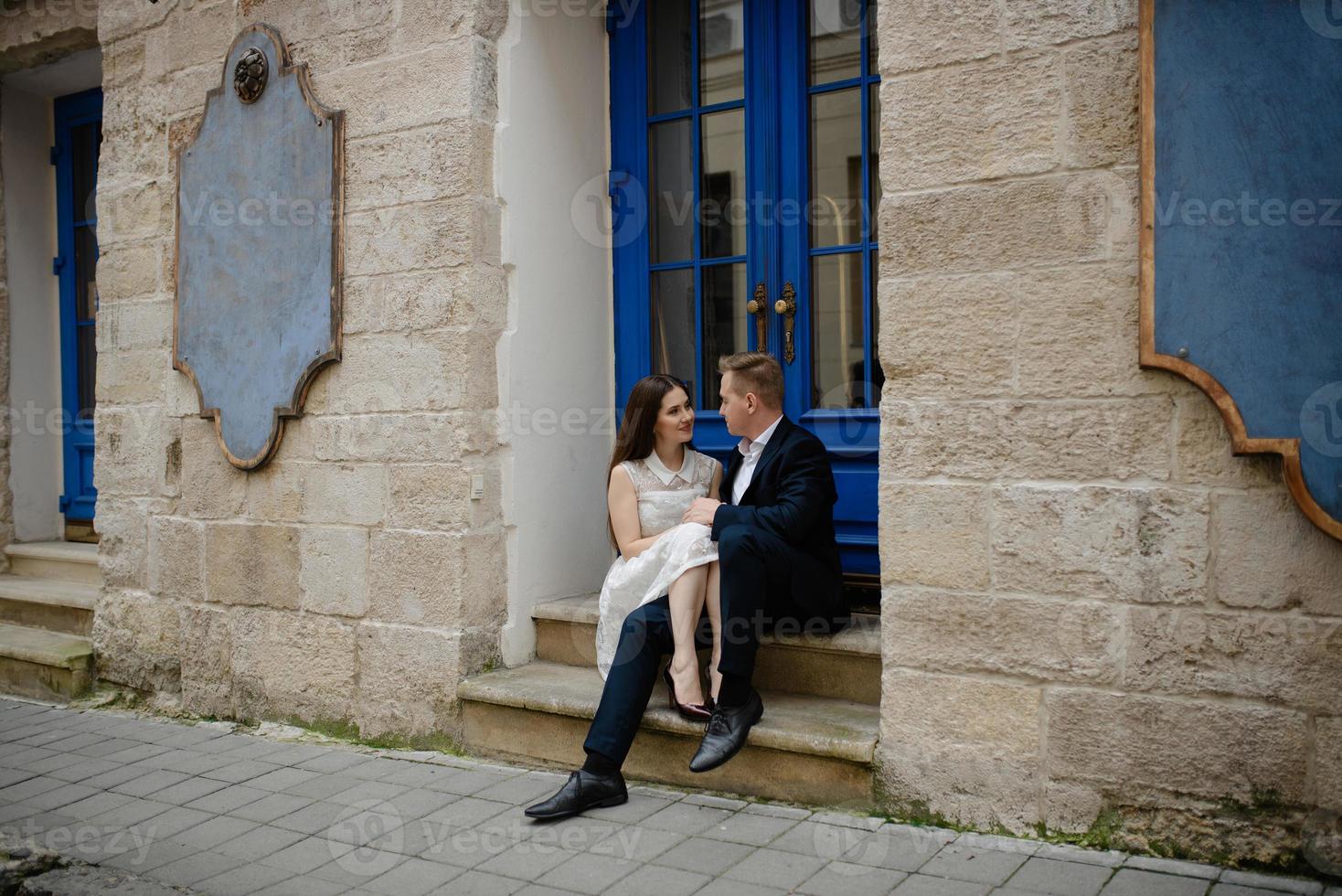 Happy smiling attractive young couple on date sitting in street cafe in summer, sharing drink, looking at each other with love, flirting, having fun together photo