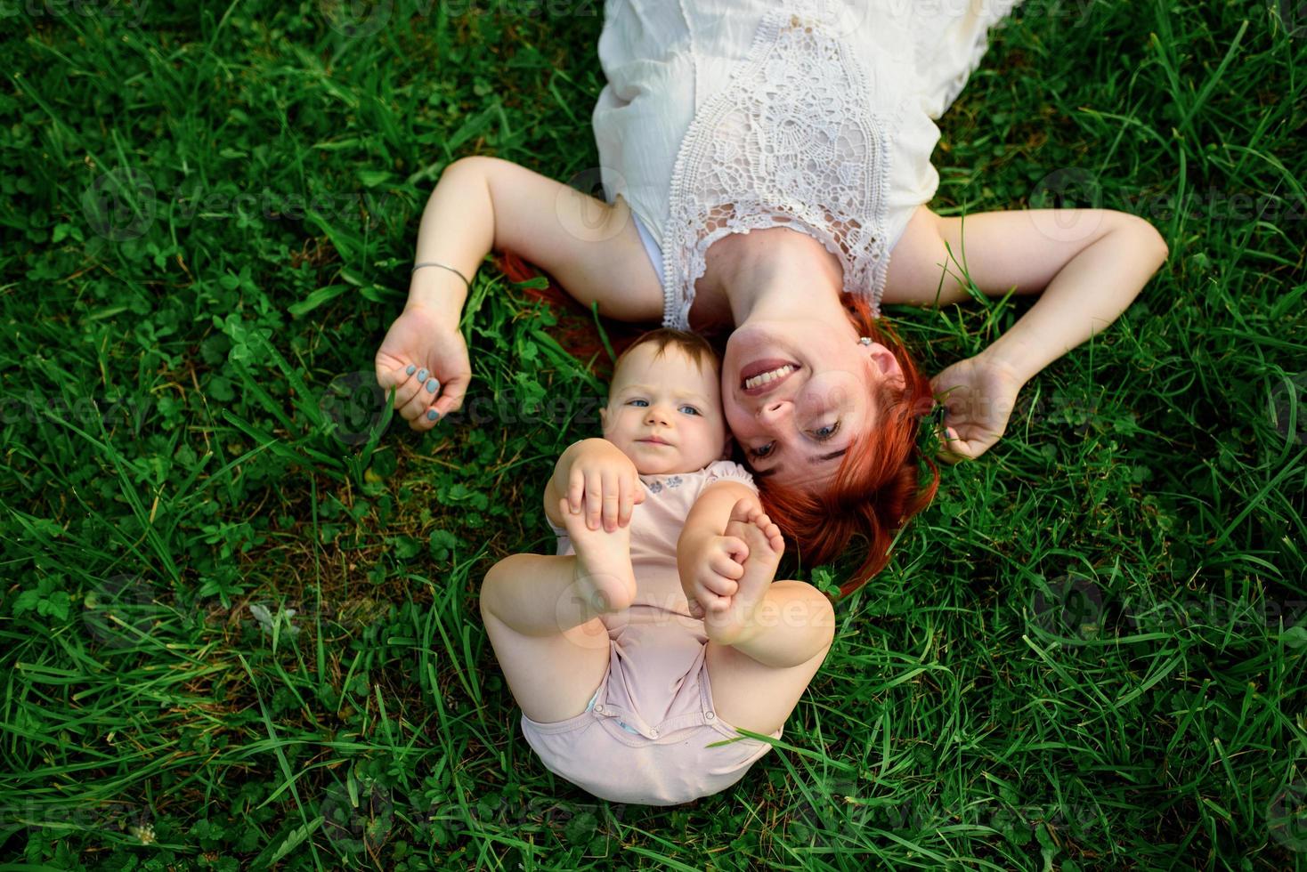 Mom hugs and plays with her one-year-old daughter wrapped in a towel after bathing. photo