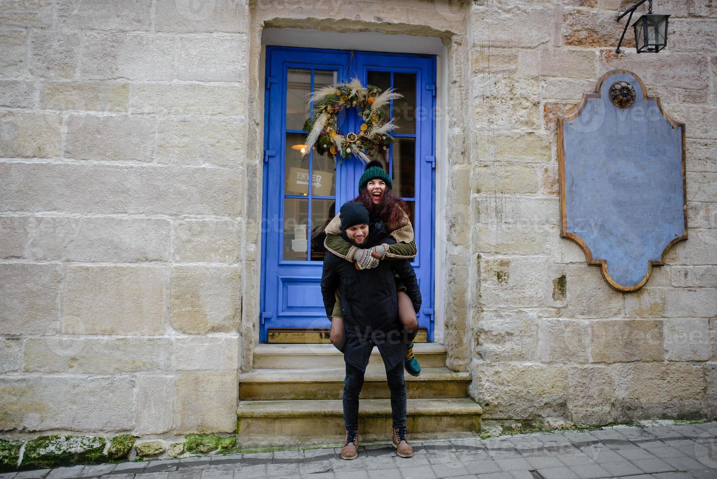 Young romantic couple is having fun outdoors in winter before Christmas. Enjoying spending time together in New Year Eve. Two lovers are hugging and kissing in Saint Valentine's Day. photo