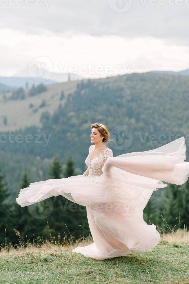 whirling bride holding veil skirt of wedding dress at pine forest photo