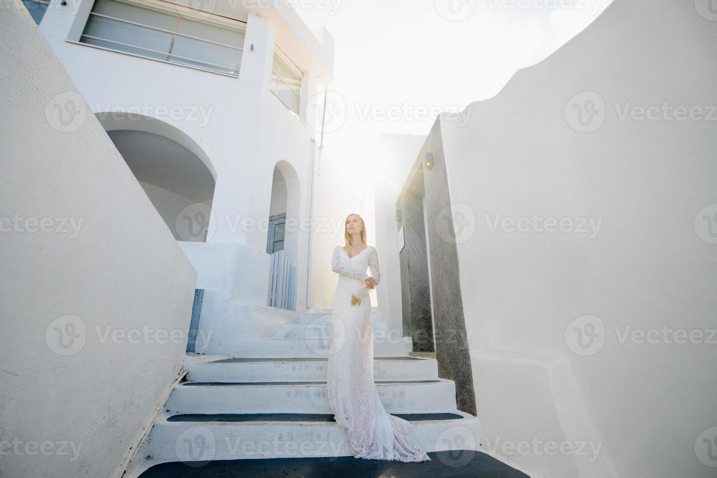 The beautiful blond hair young women bride blue in a wedding white long sexy dress on Santorini in Greece photo