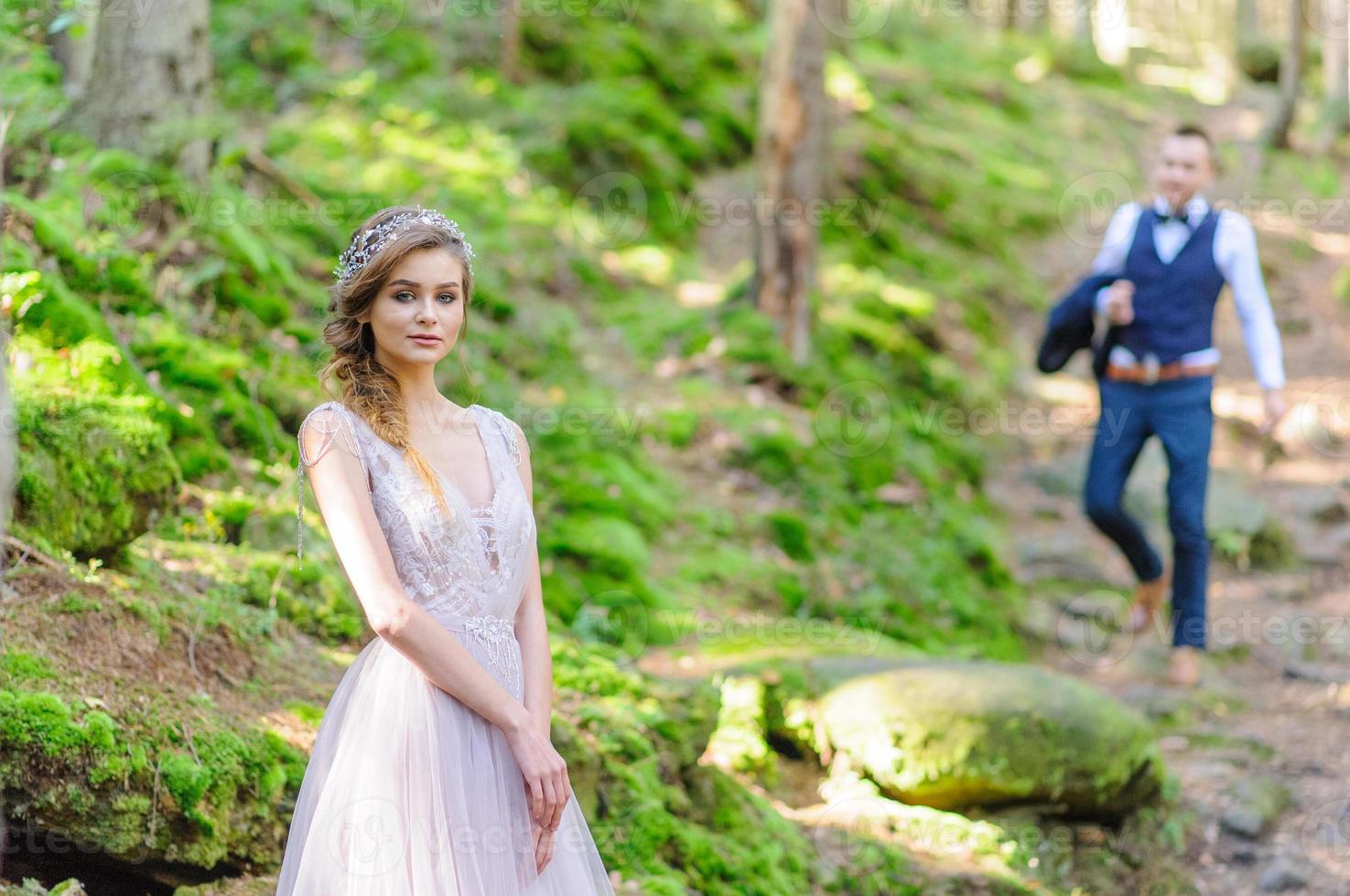 una atractiva pareja de recién casados, un momento feliz y alegre. un hombre y una mujer se afeitan y se besan con ropa de fiesta. ceremonia de boda de estilo bohemio en el bosque al aire libre. foto