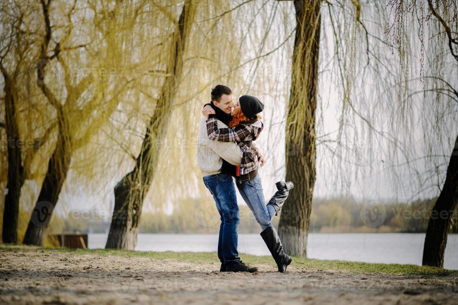 Young couple walks in autumn forest. Man giving his girlfriend piggyback. People having fun outdoors photo