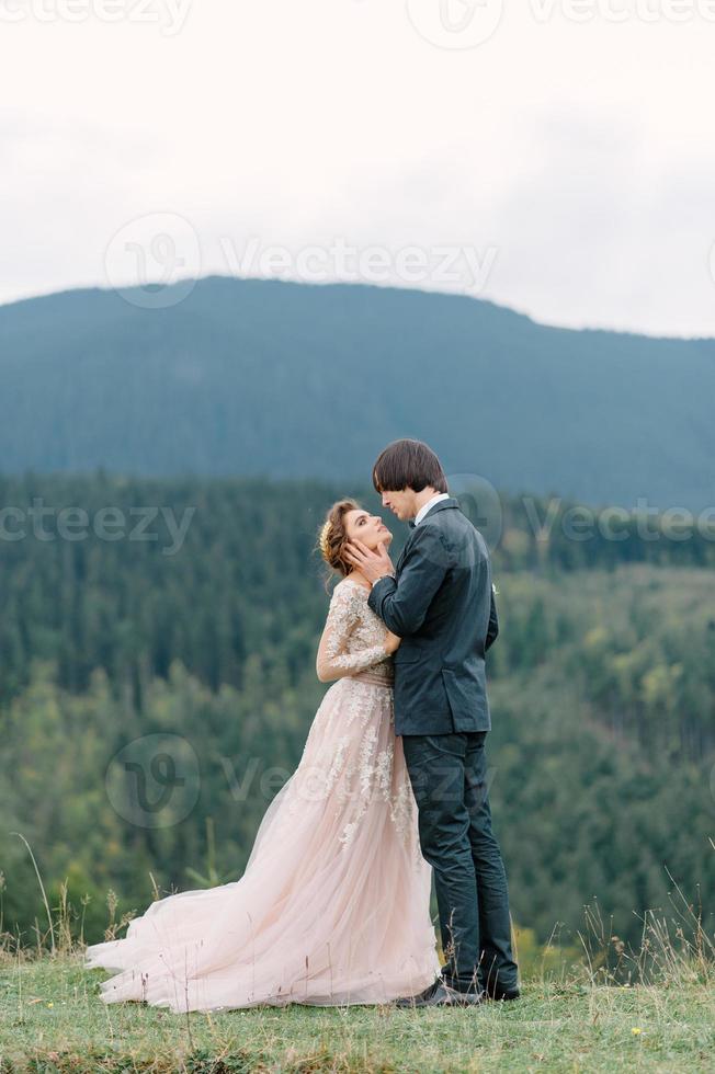 Stylish young bride and groom stand in boat on background cloude sky sea and mountains of Montenegro photo