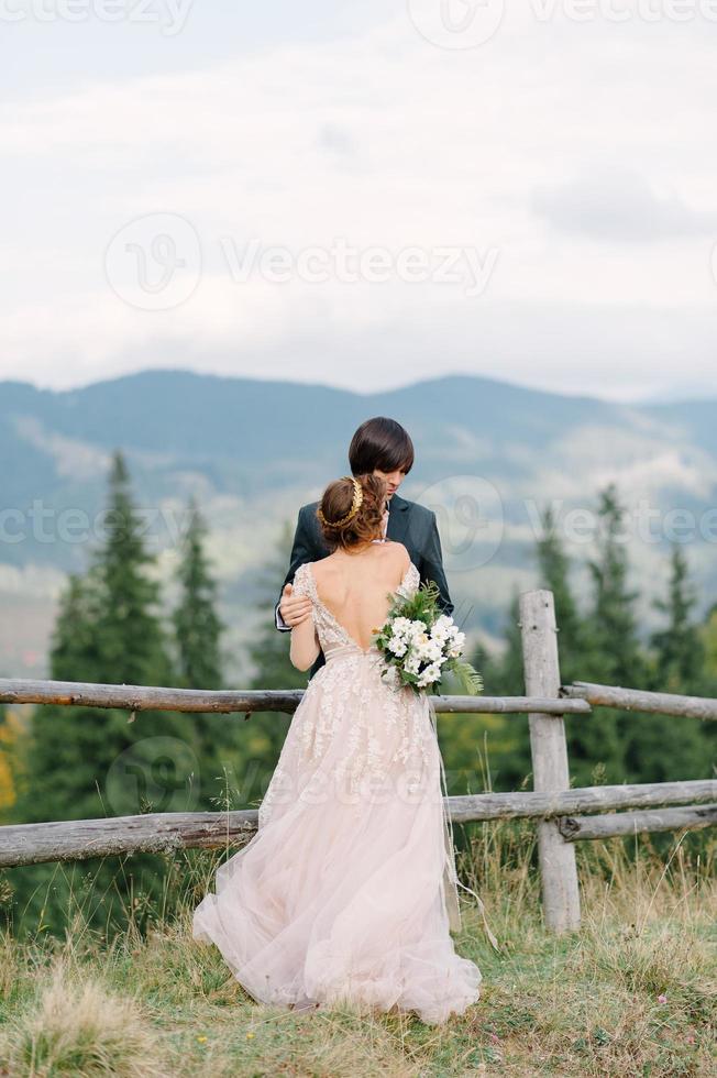 Beautifull wedding couple kissing and embracing near the shore of a mountain river with stones photo