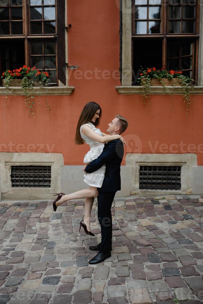 Couple in love kissing laughing having fun. Dating interracial young couple embracing on date. Pretty summer sunny outdoor portrait of young stylish couple while kissing on the street. Relationships photo