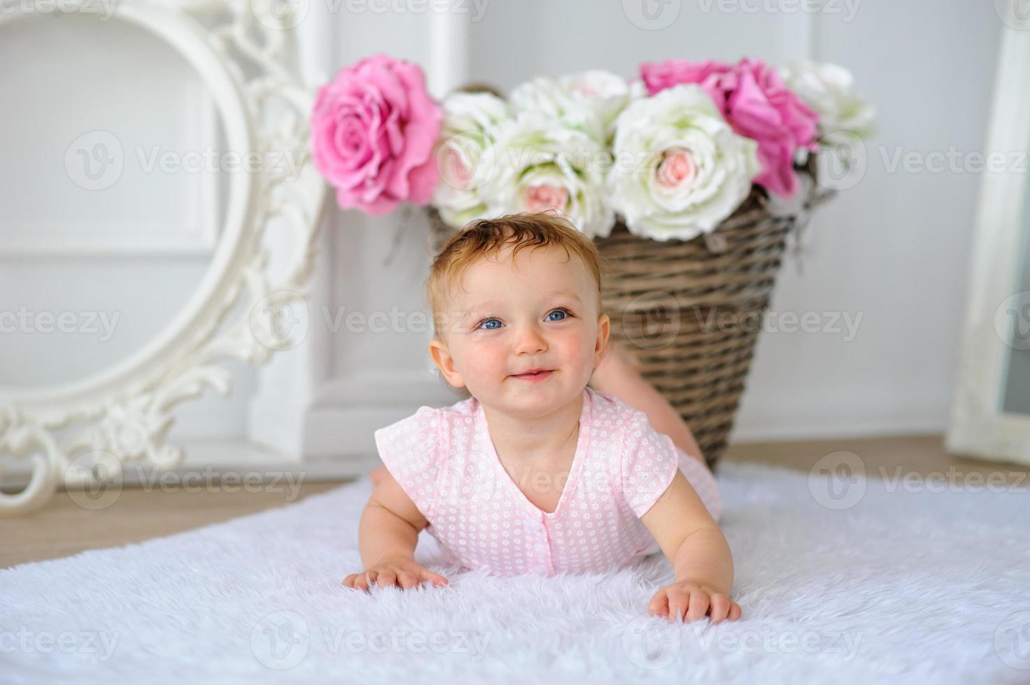 The little one-year-old girl smiles and sits. photo