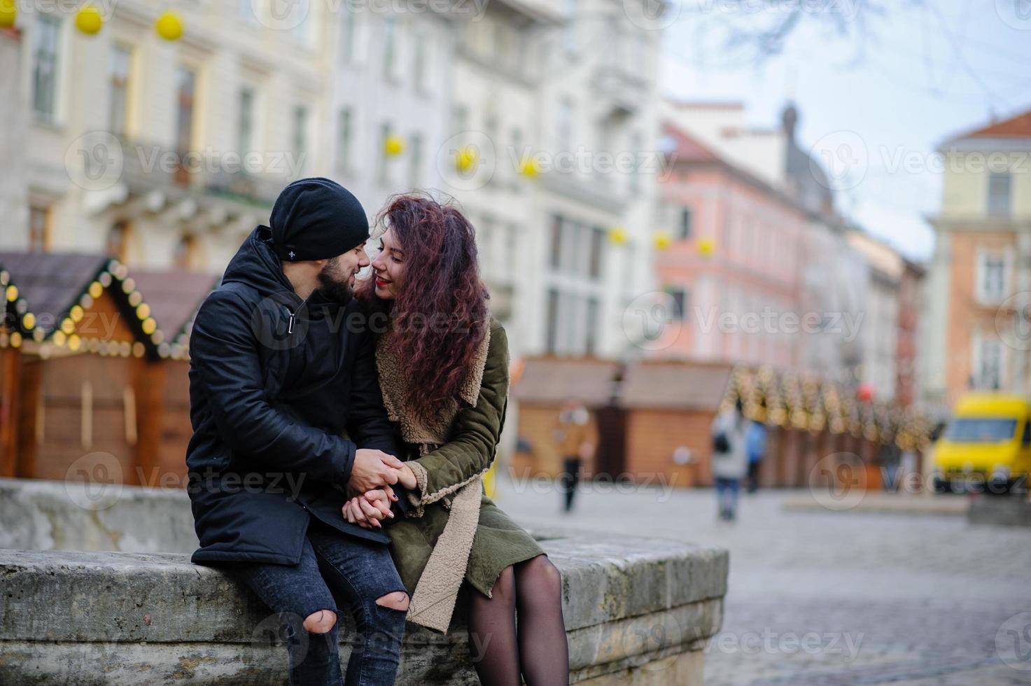 pareja amorosa y elegante en una ciudad primaveral parada cerca de ventanas con pequeñas lámparas foto